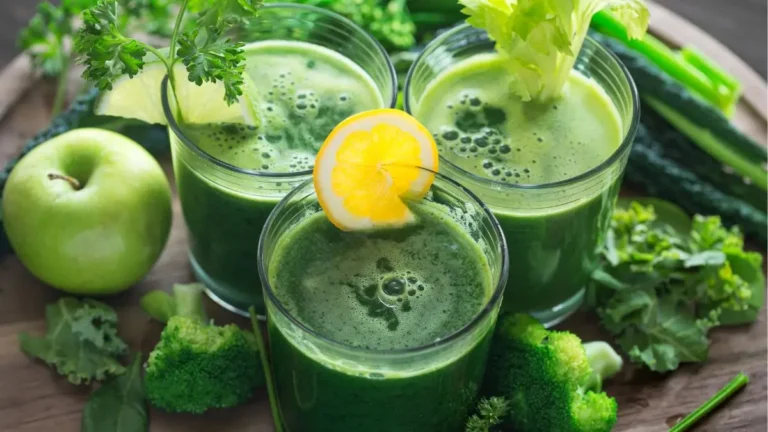 Tres vasos de Jugo verde rodeado de verduras y una manzana verde