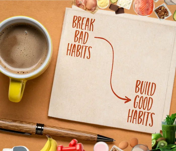 Break bad hábits and buid good habits escrito en una hoja de papel, encima de la mesa con una taza de chocolate a la izquierda
